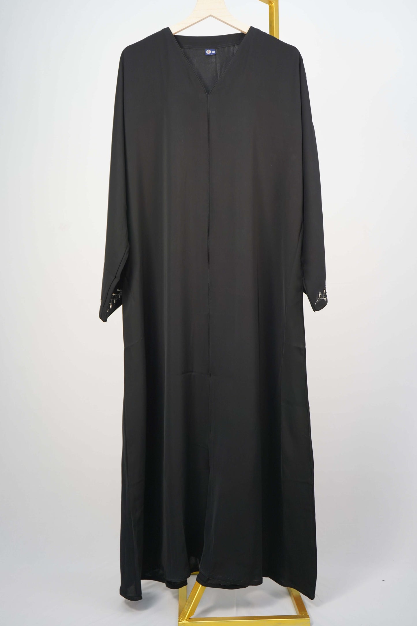 A full shot of the black Korean Nidha Abaya hanging, highlighting the V-neck and and the flowing fabric.