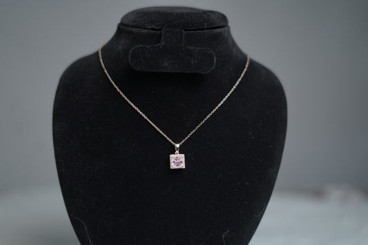 Lavender cubic zirconia necklace with gold chain on jewelry stand.