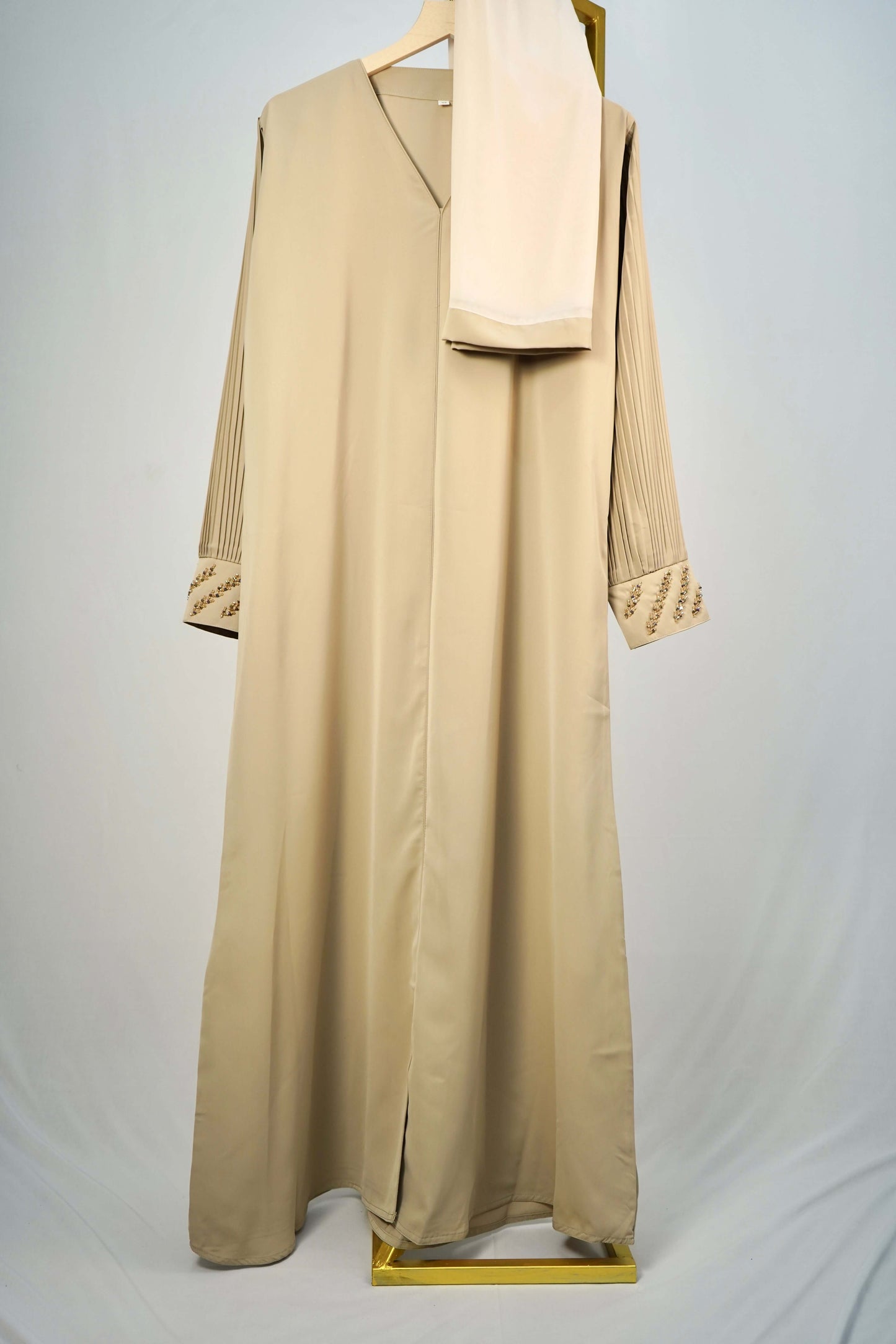 A full shot of the Korean Alqa Nidha Abaya in Light Beige, hanging with its matching scarf.