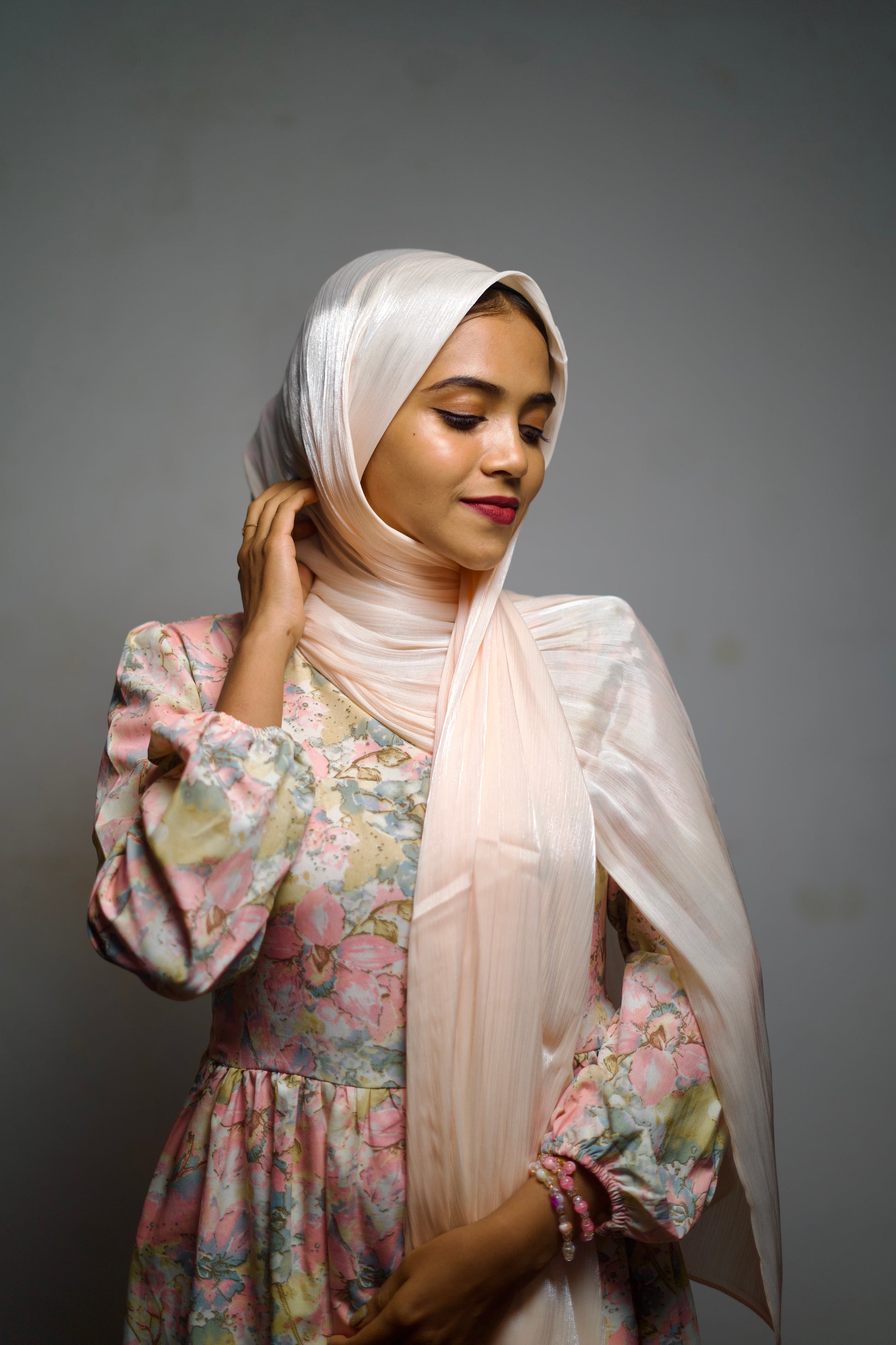 Millennial pink shimmer hijab softly wrapped, reflecting a delicate glow.