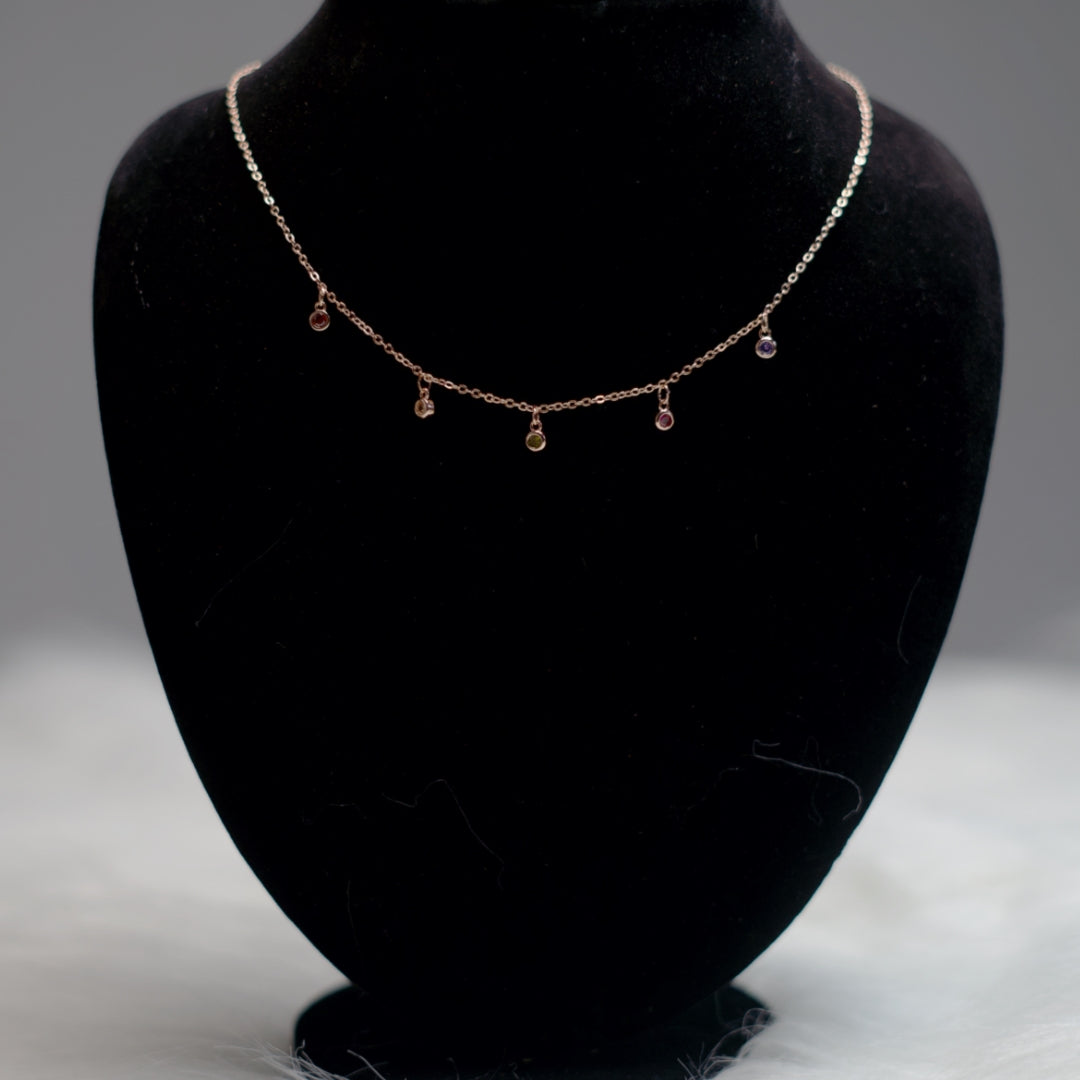 Rose gold chain with multicolor stone pendants.