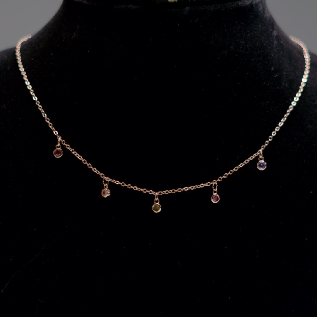 Rose gold chain with multicolor stone pendants.