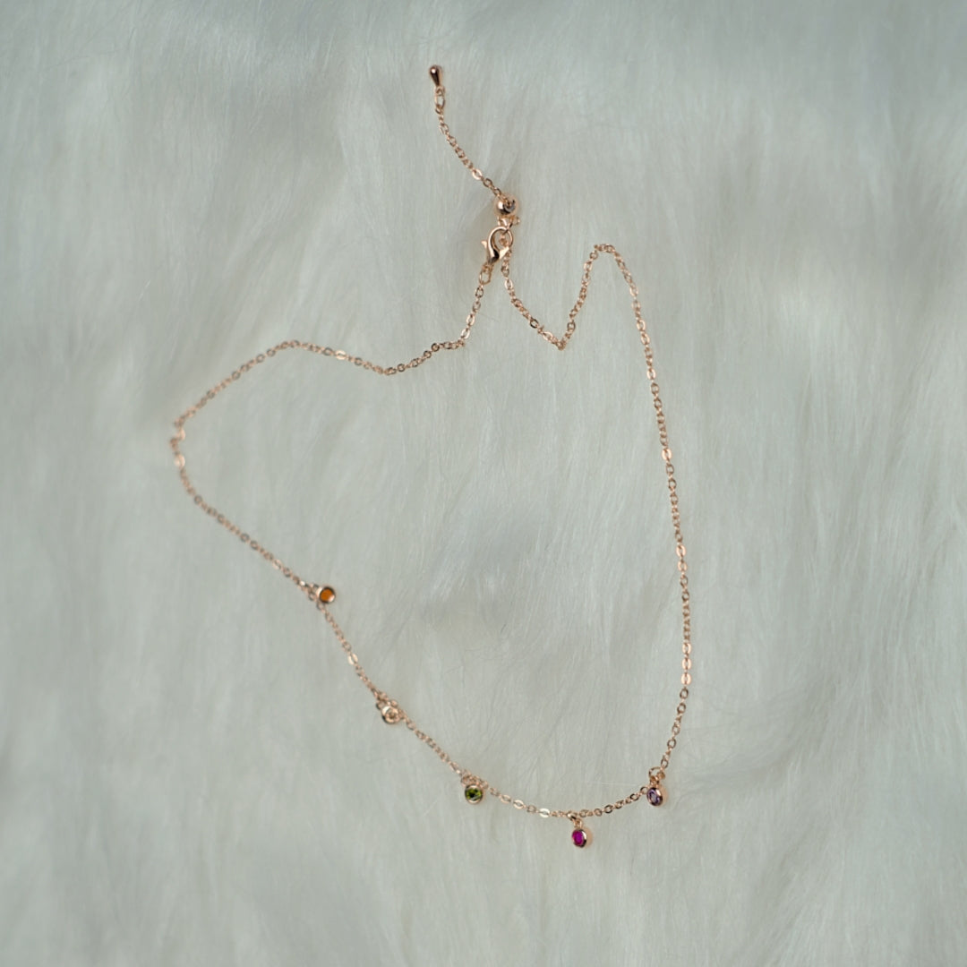 Rose gold chain with multicolor stone pendants.