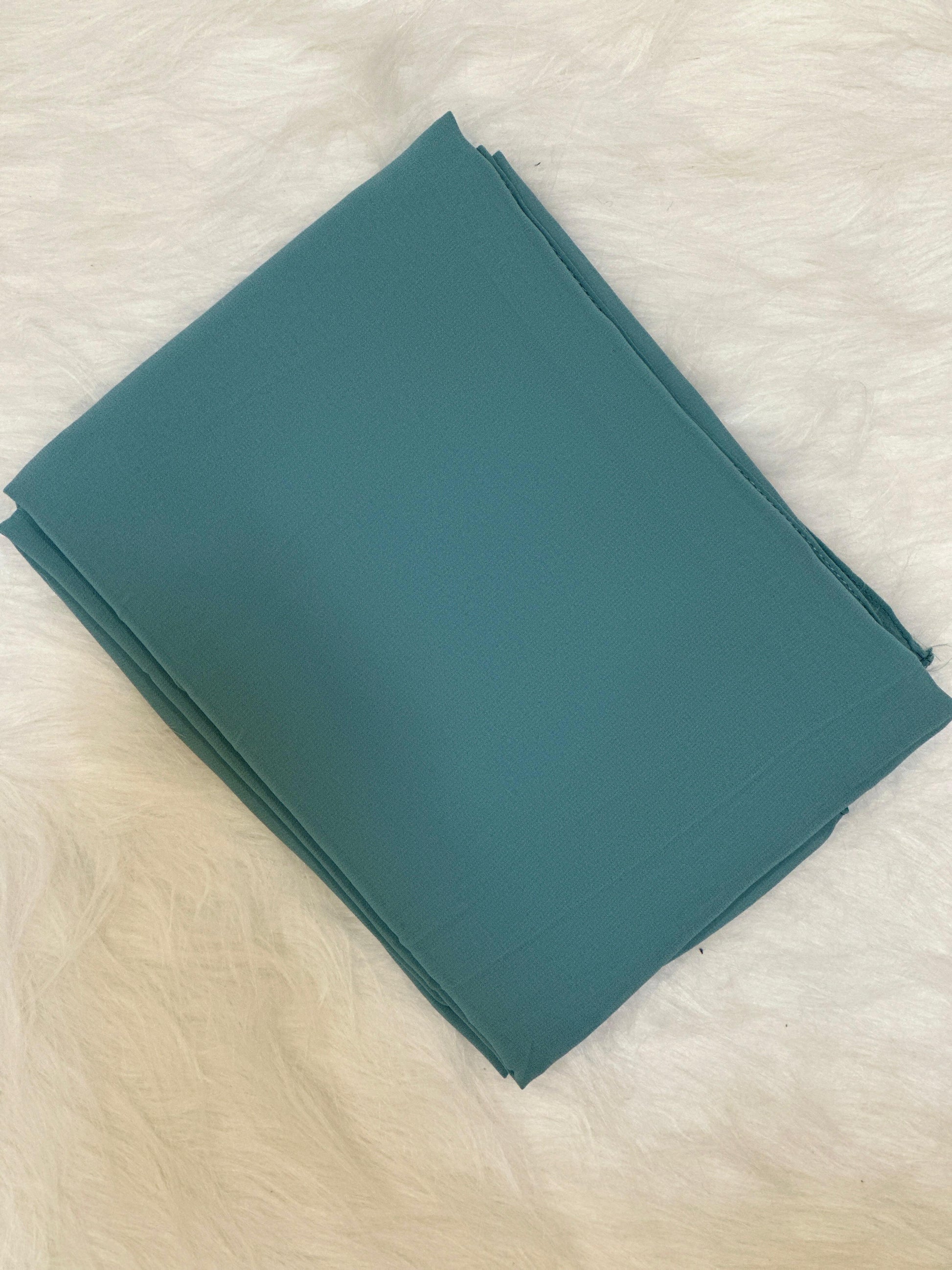Close-up of a folded chiffon scarf in mint green, soft and sheer.
