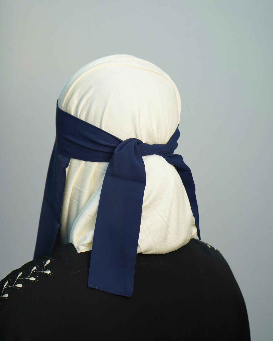 Back view of navy blue niqab tied securely over a white undercap.