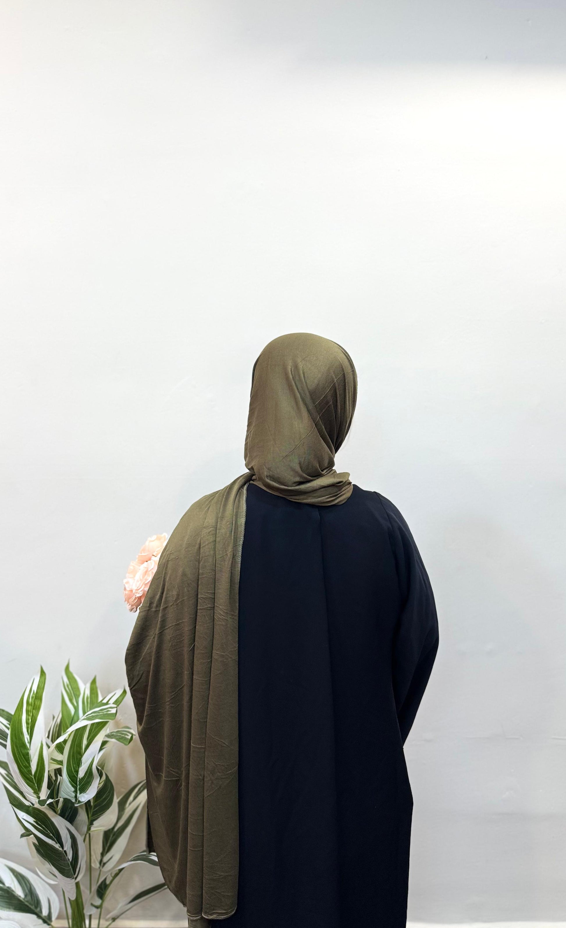 Olive green jersey hijab styled over shoulders with ease.