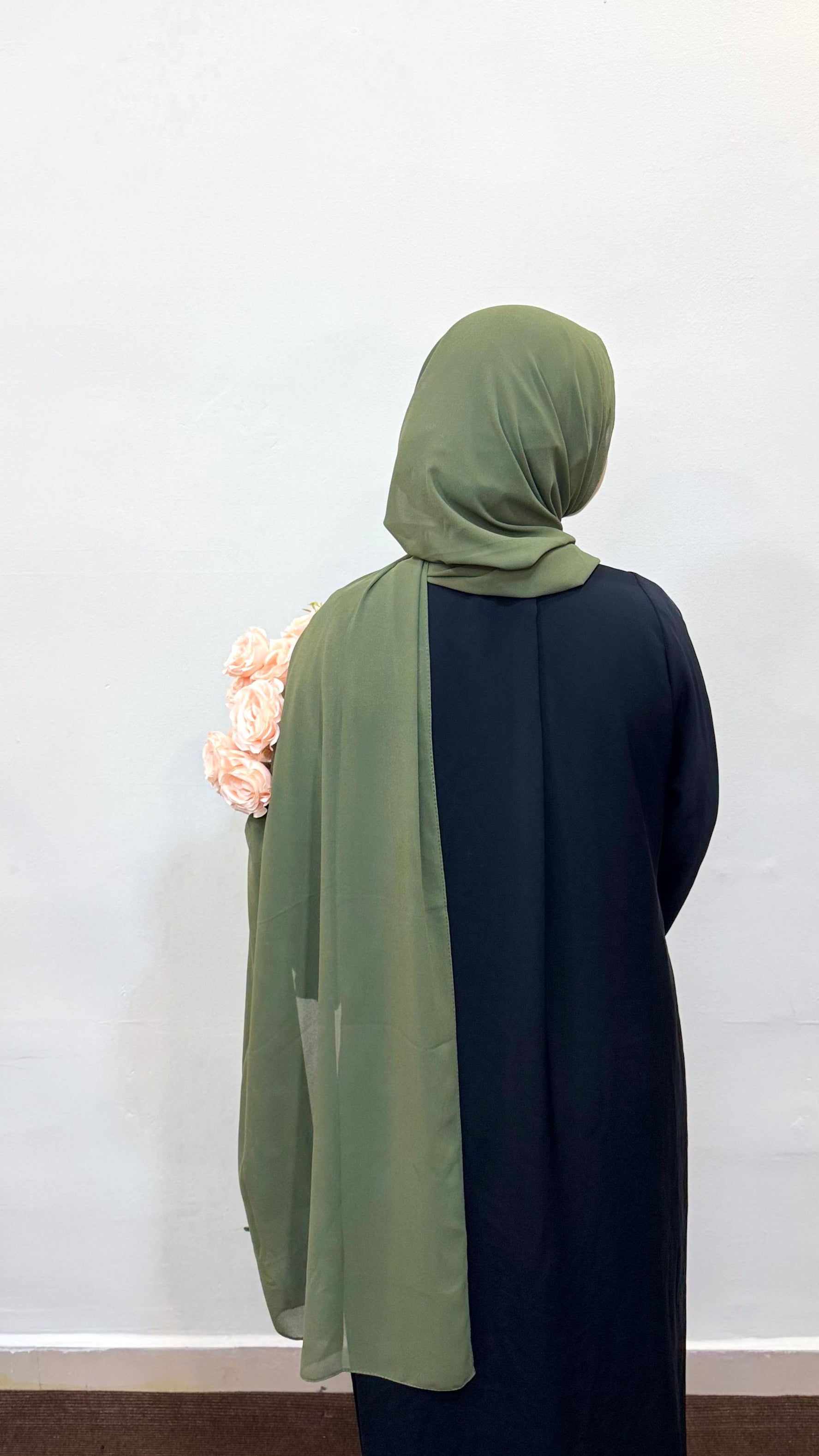 Back profile of a woman wearing an olive green scarf over a full pardha.