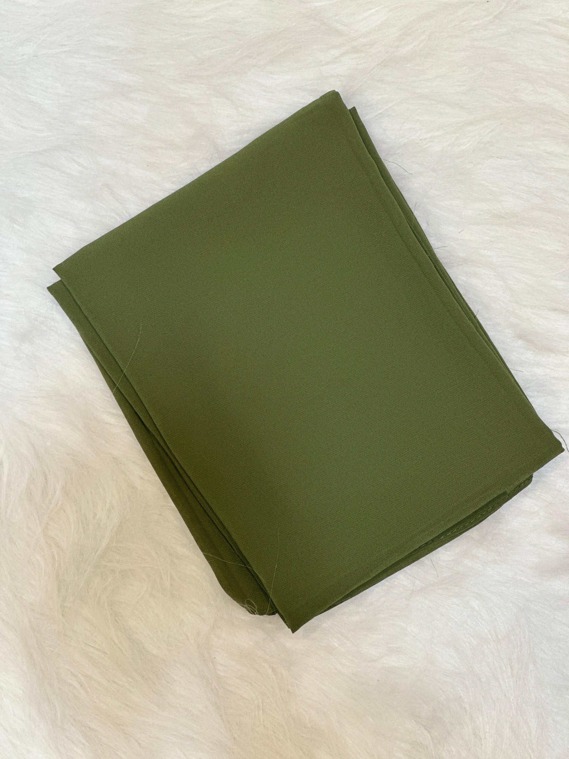 Olive chiffon scarf placed in folded form with subtle light reflection.