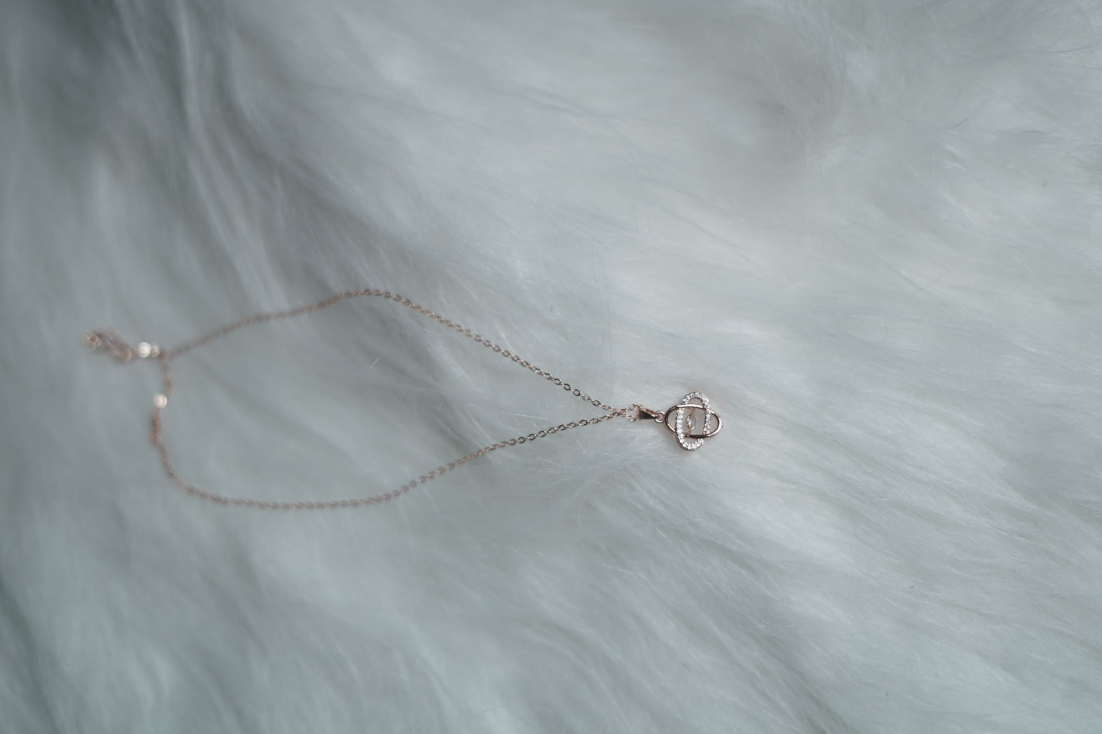 Rose gold orbital pendant necklace on white background.