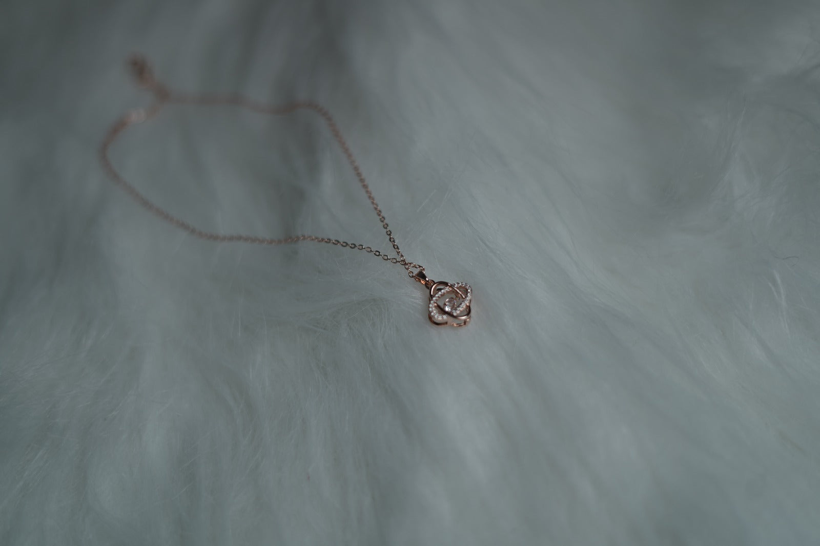 Orbit Luxe Necklace placed on white fur background with rose gold glow.