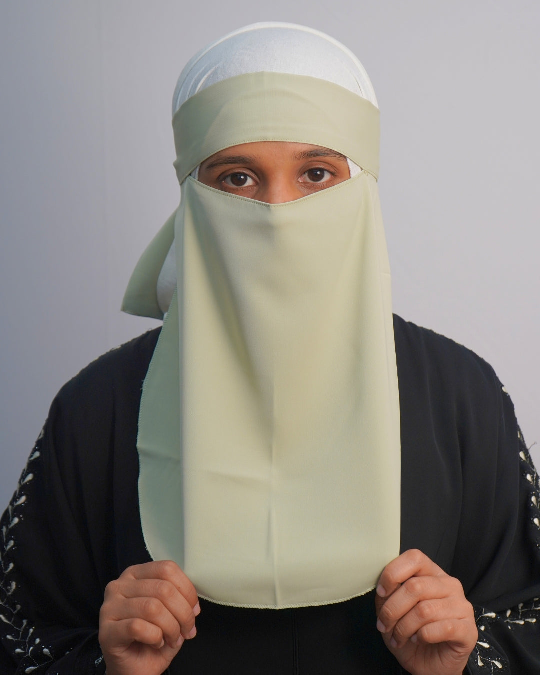 Front view of pastel green tie-back niqab with full coverage and eye opening.