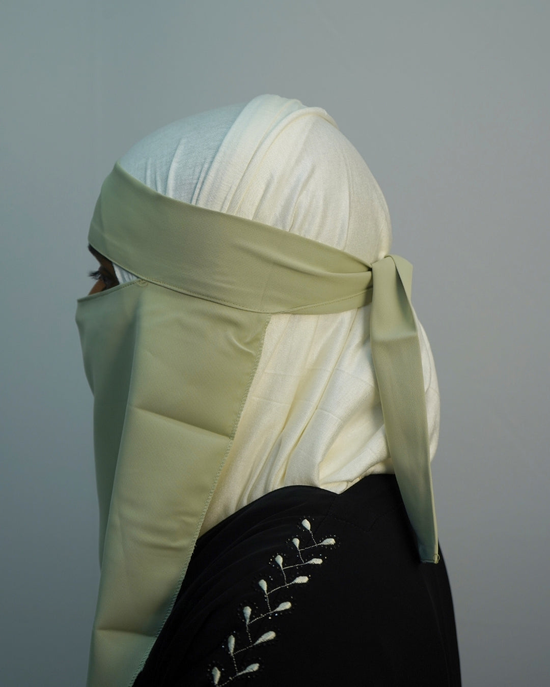 Side view of pastel green niqab with adjustable tie-back straps.