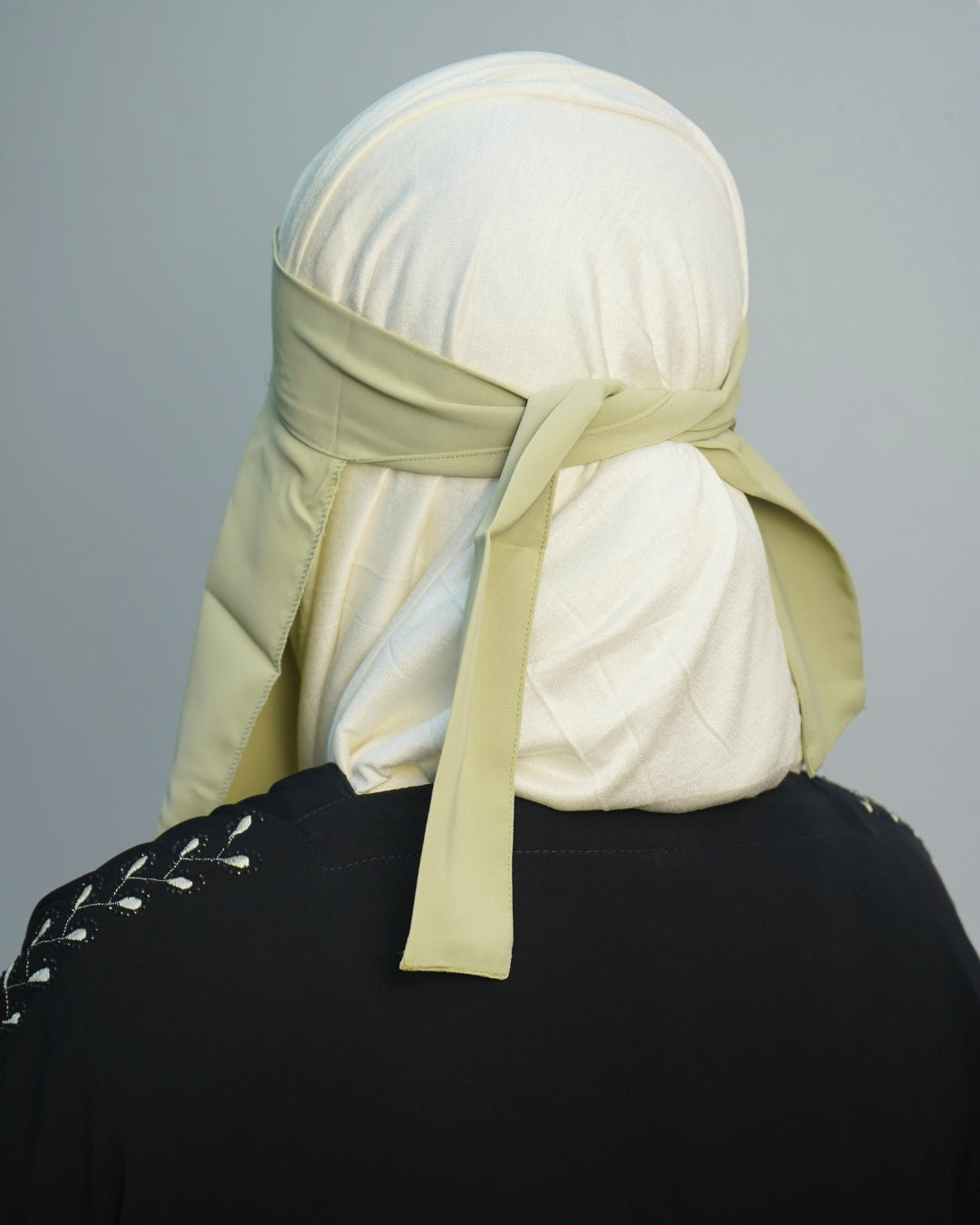 Back view of pastel green niqab tied securely over white hijab.