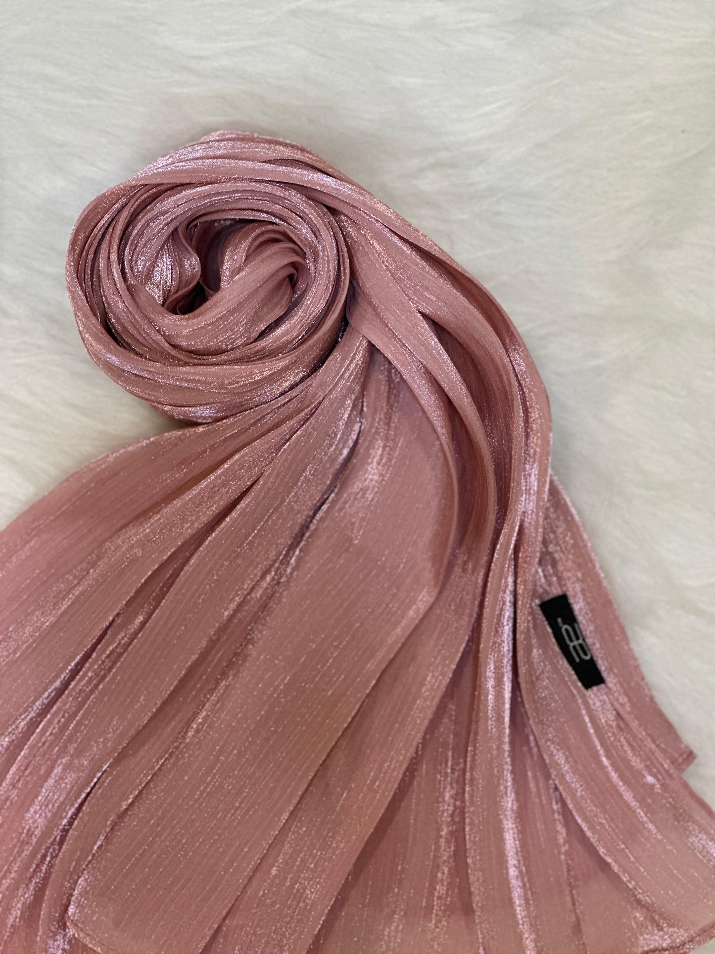Round swirl of a pink hijab showing glossy fabric and smooth layers.