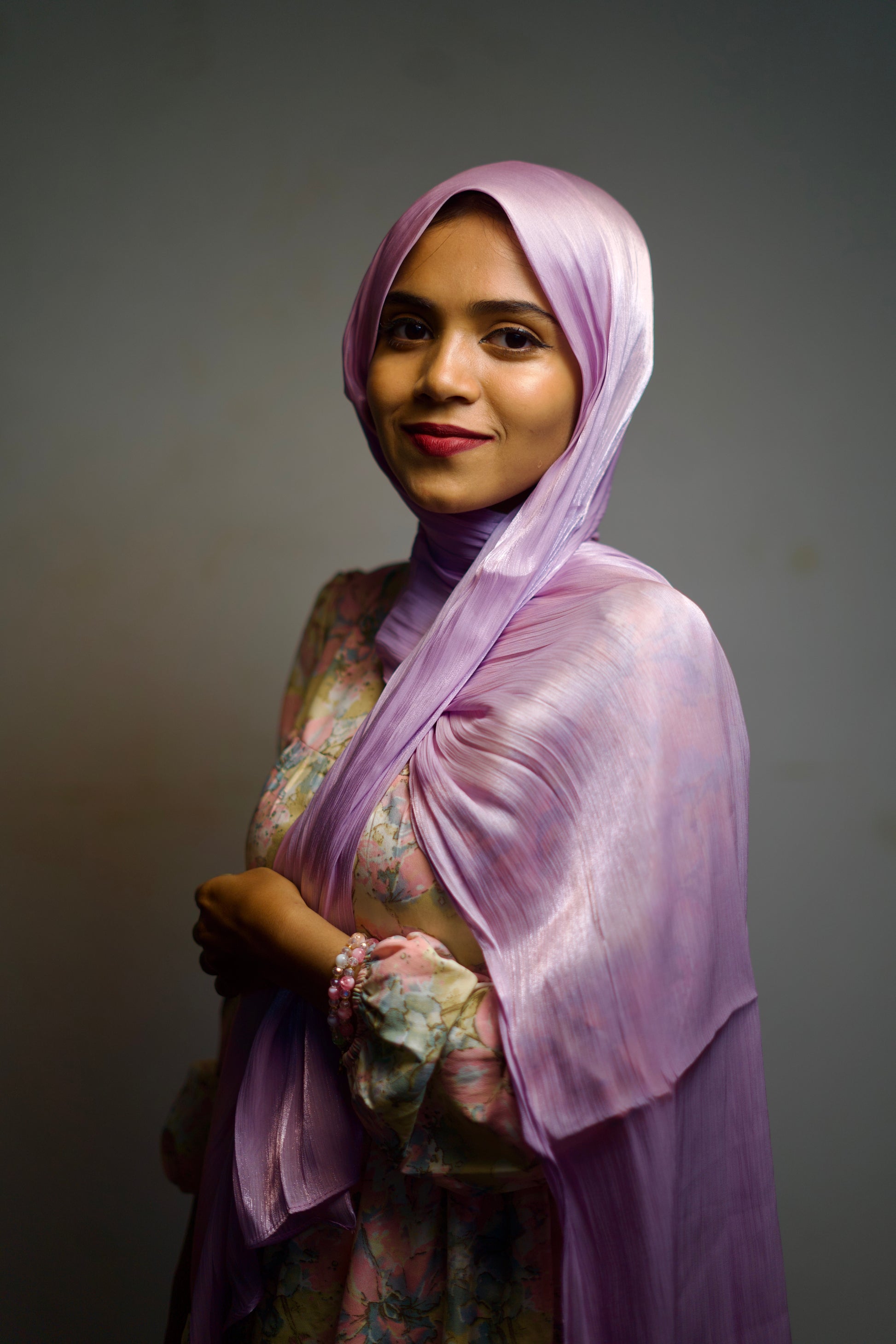 Woman in a plum-toned shimmer scarf, softly draped around the face.