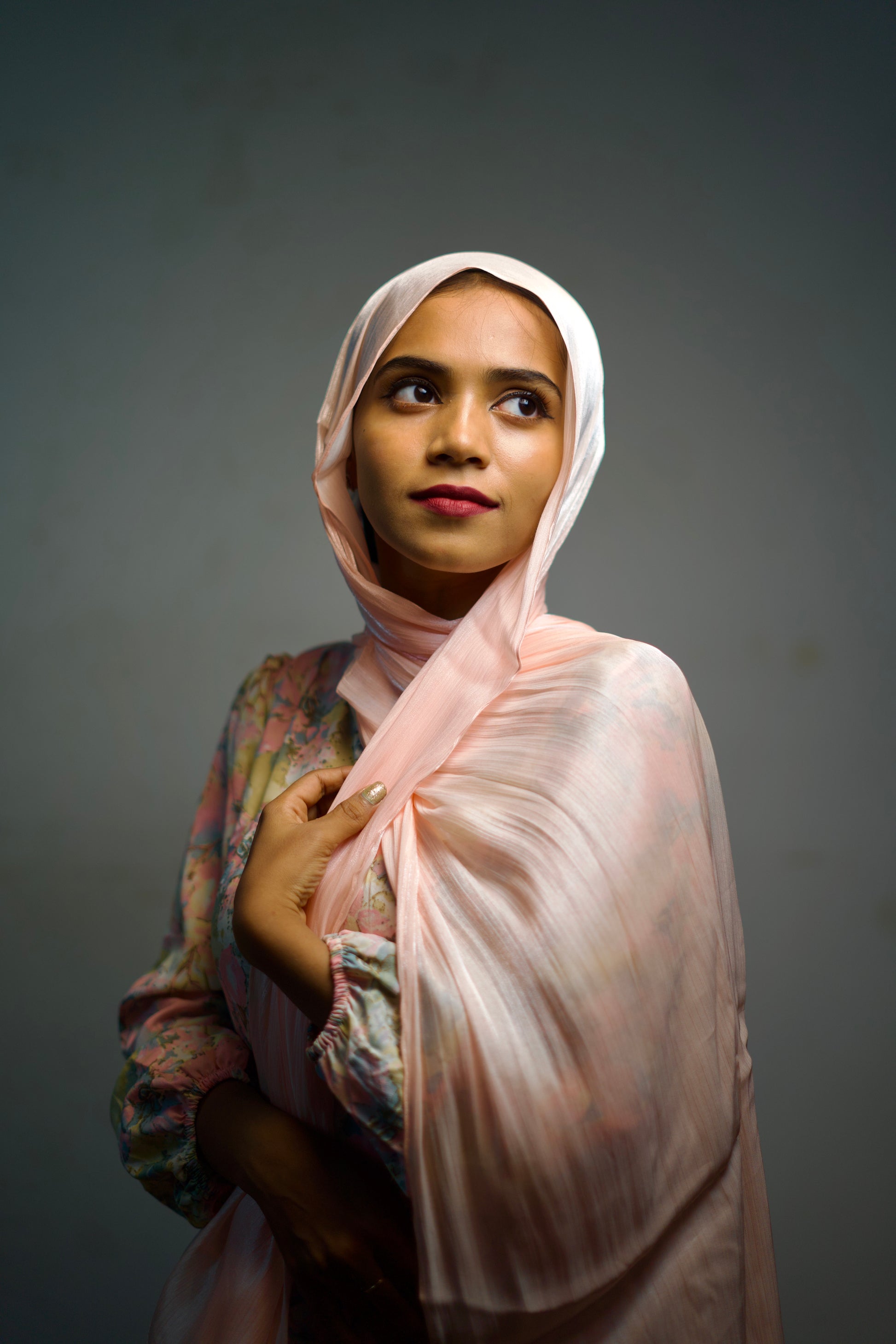 Woman wearing a rose gold hijab with light shimmer and smooth folds.