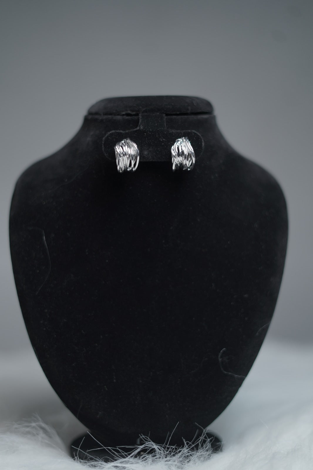 Sculpted silver hoops displayed on earring stand.