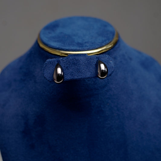 Close-up of smooth silver stud earrings shaped like gentle water droplets.