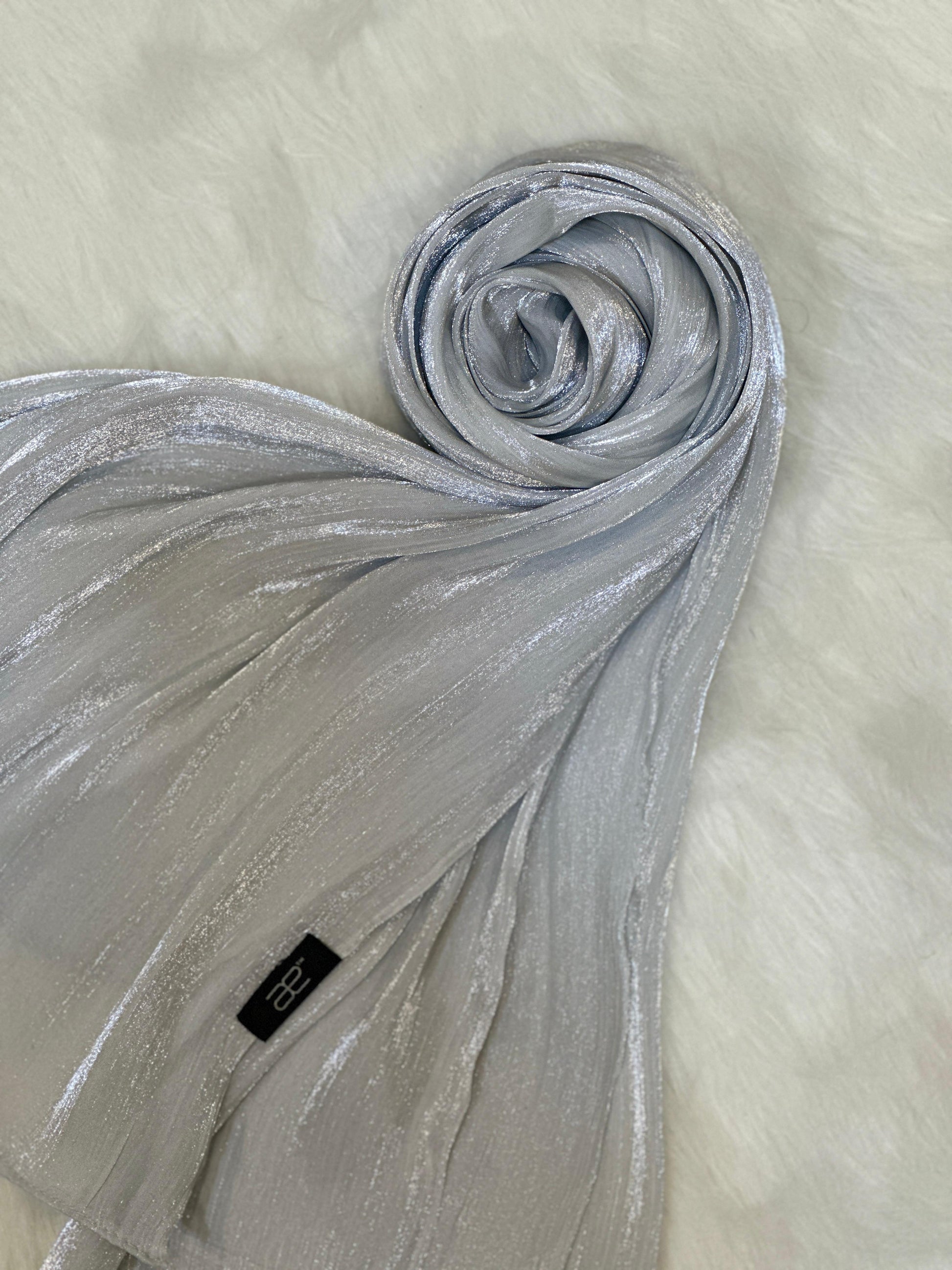 Round display of a silver chiffon scarf with light shimmer texture.
