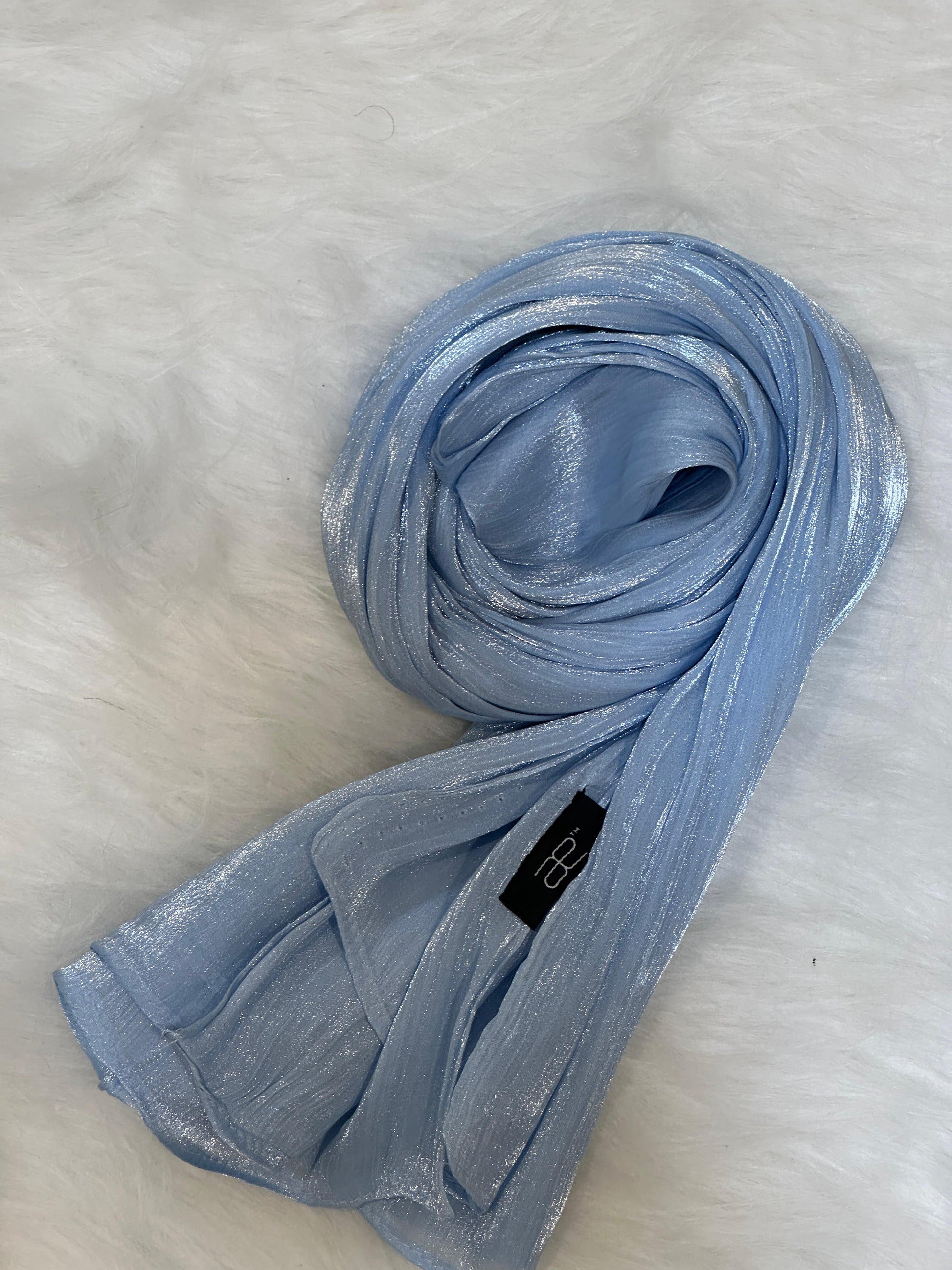 Sky blue shimmer scarf displayed in a circular rolled shape.
