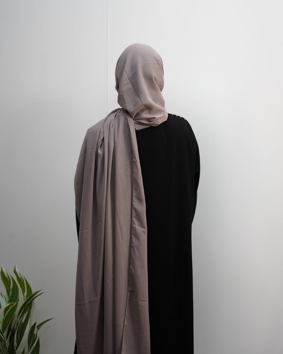 Back view of a woman wearing a taupe Indian chiffon hijab with a black abaya.