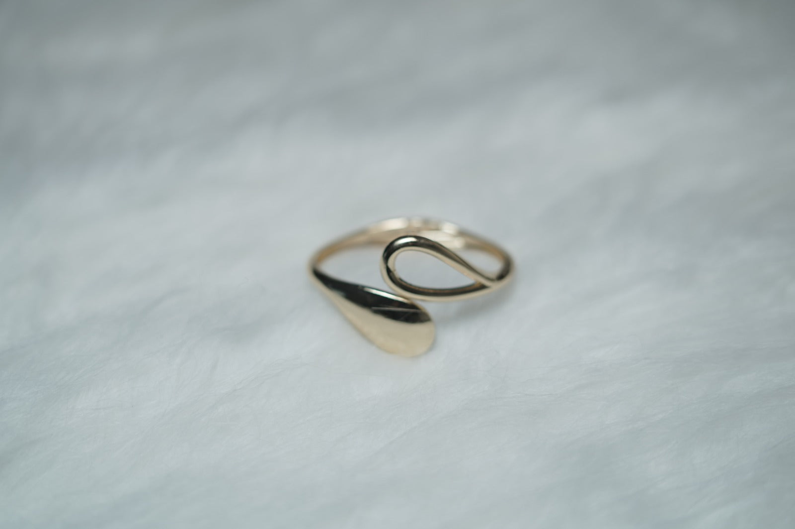 Close-up of gold bangle ends – one teardrop cutout, one polished leaf form.