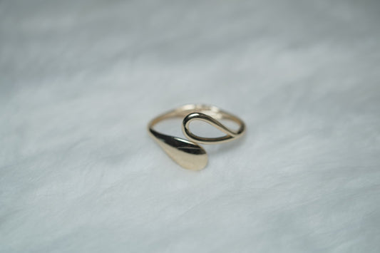 Close-up of gold bangle ends – one teardrop cutout, one polished leaf form.