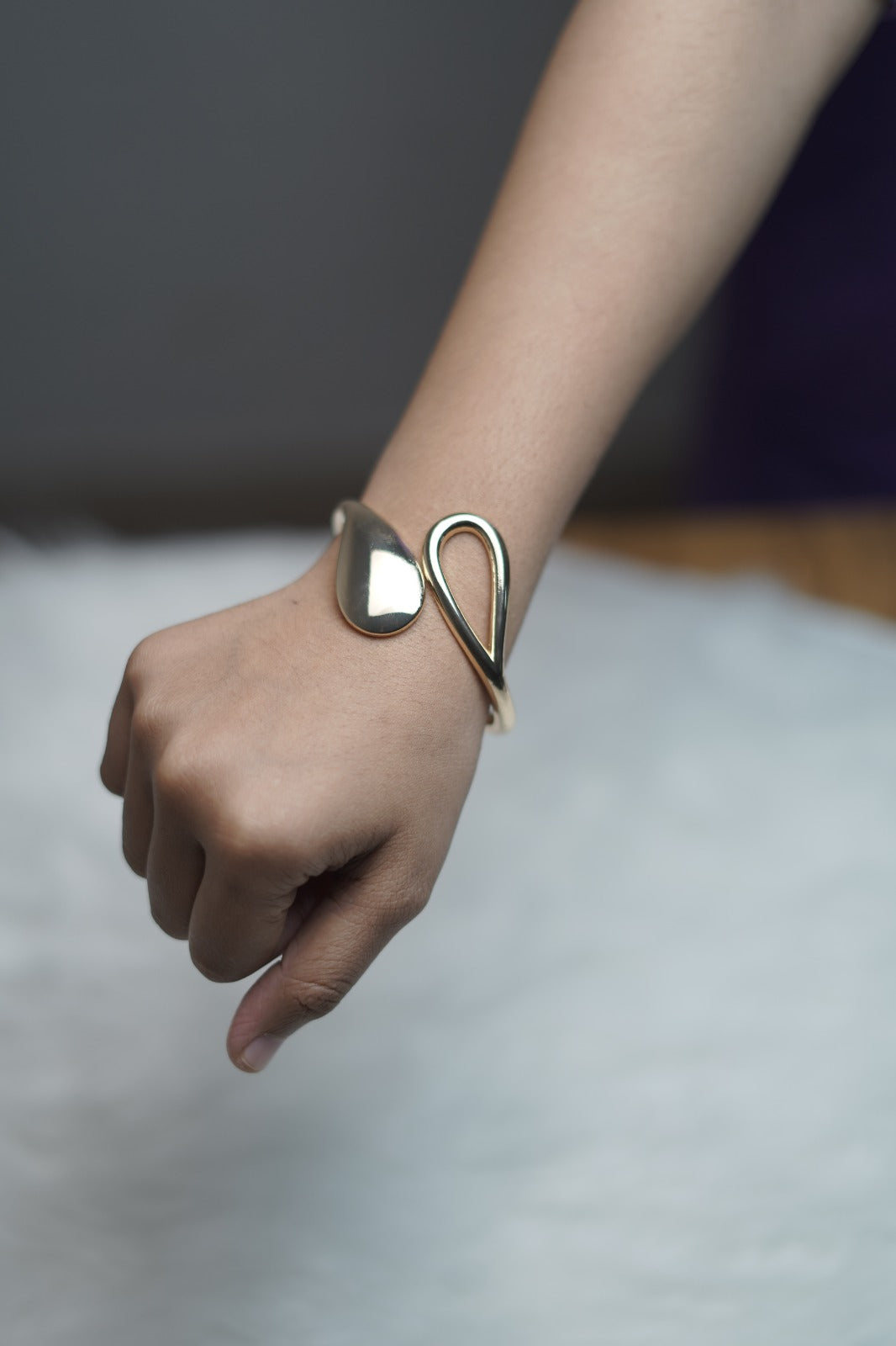 Modern minimalist bracelet worn, featuring teardrop and leaf accents in gold.