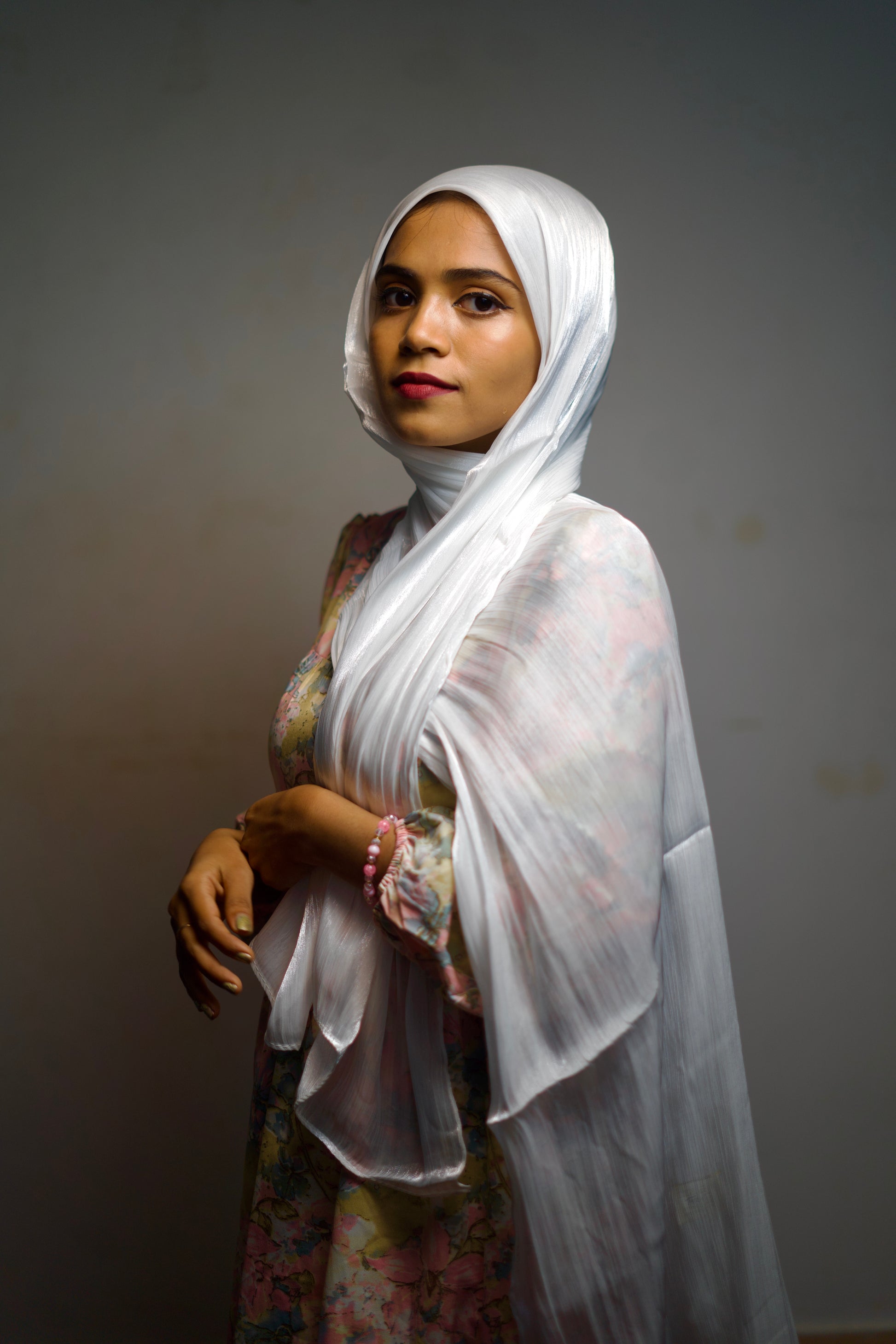 White shimmer scarf worn in a front wrap, glowing under soft light.