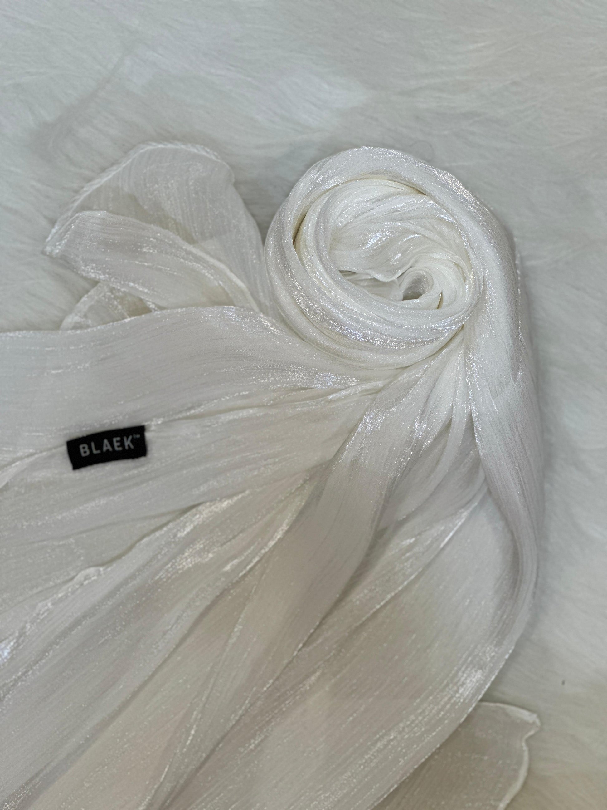 White shimmer hijab coiled into a round swirl, showcasing its delicate shine.