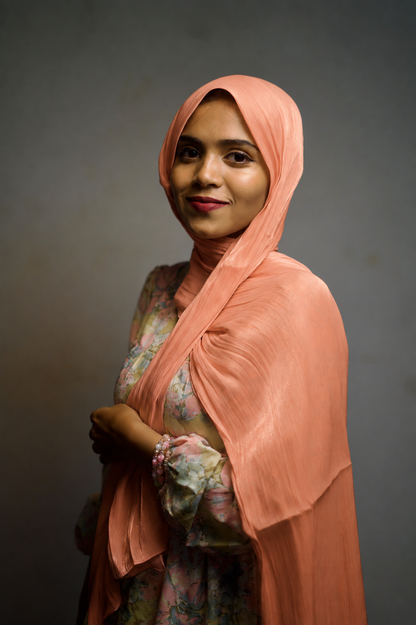 Woman wearing Atomic Tangerine shimmer hijab with elegant draped styling.