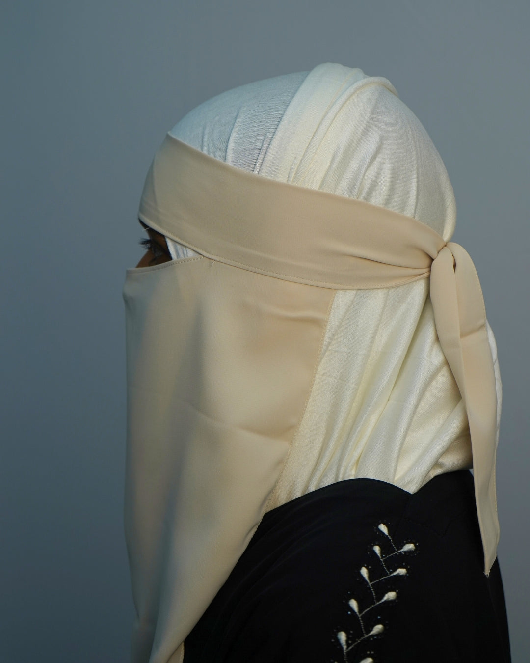 Side view of lightweight beige niqab showing adjustable chiffon straps.