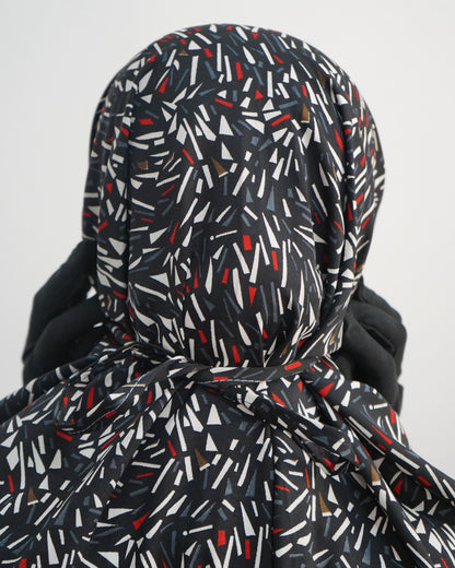 Close-up of black prayer dress back tie with abstract red, white, and grey print.