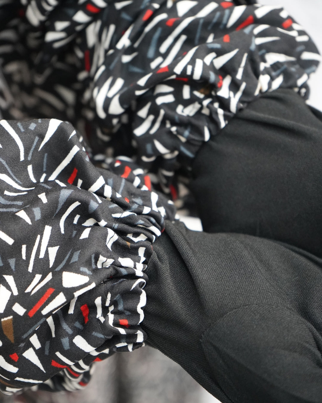 Close-up of elasticated sleeve cuff of black abstract printed prayer dress.