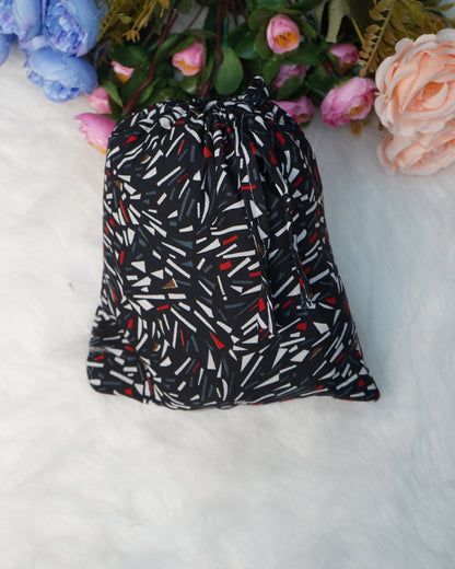 Compact matching fabric pouch in black abstract print placed on white fur background.