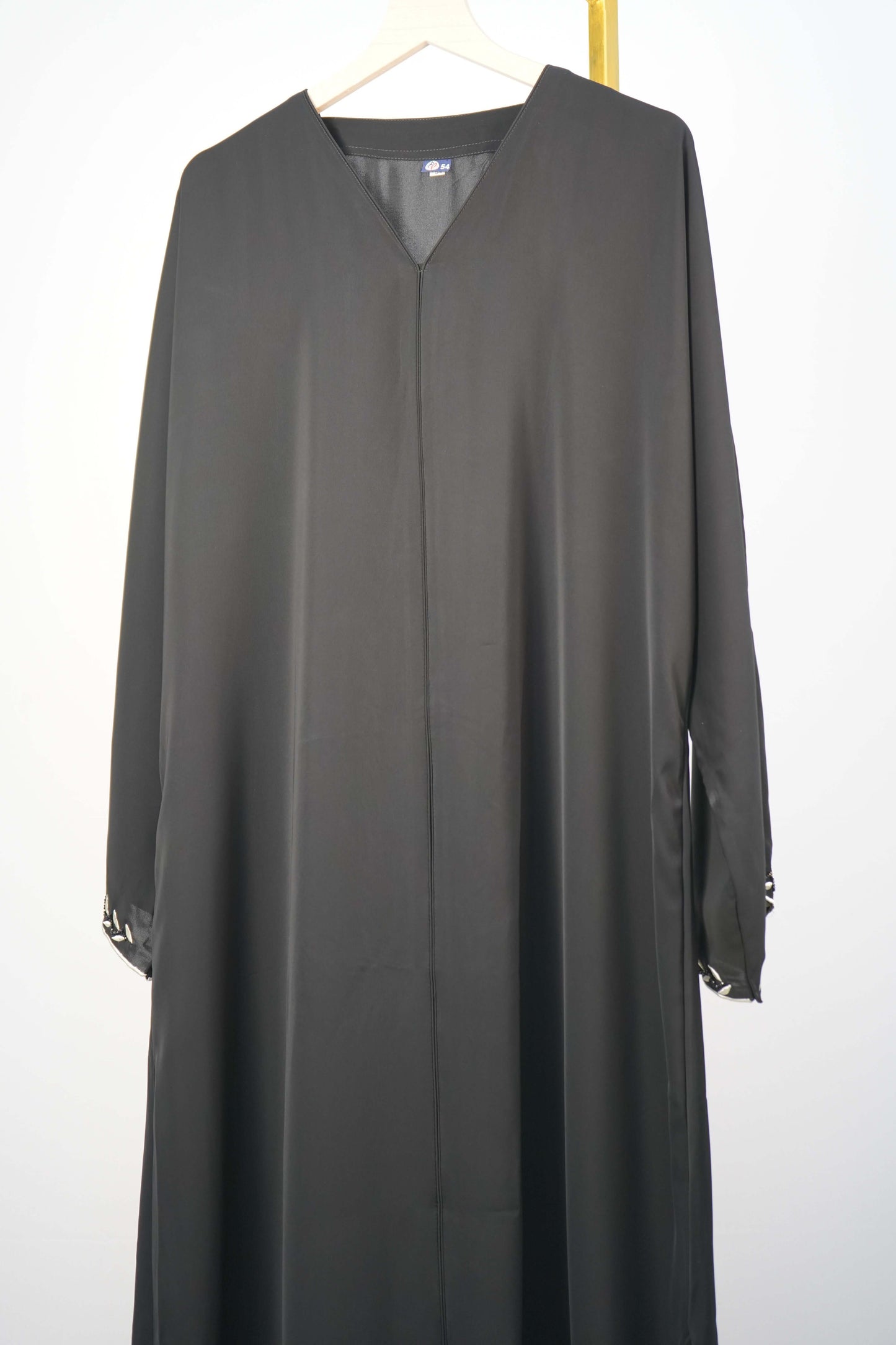 black Korean Nidha Abaya hanging, highlighting the silky fabric and V-neck.