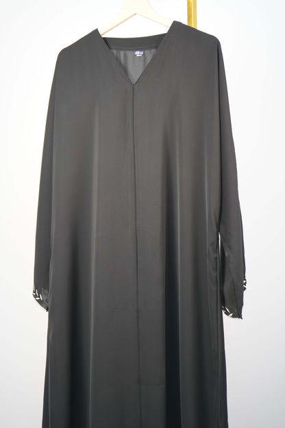 black Korean Nidha Abaya hanging, highlighting the silky fabric and V-neck.