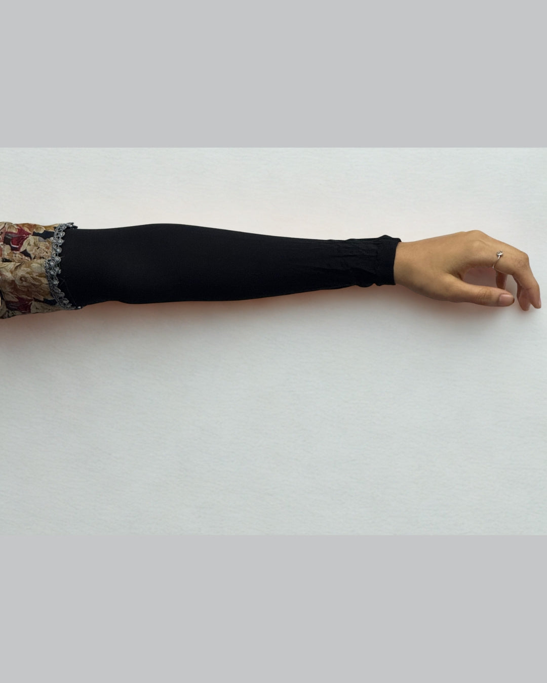 Comfortable black sleeve extender worn on the arm for modest layering.