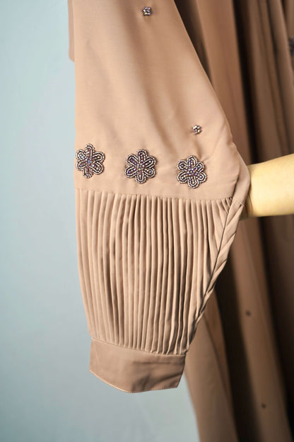 A close-up of the pleated cuff and the beaded floral design on the sleeve of the brown abaya.