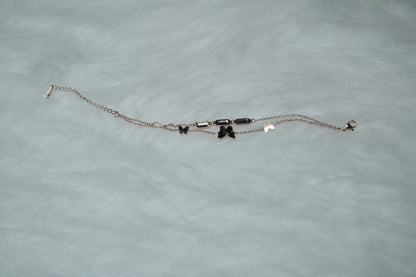 Butterfly Garden Bracelet laid flat on white fur, showcasing double chains and clear accents.