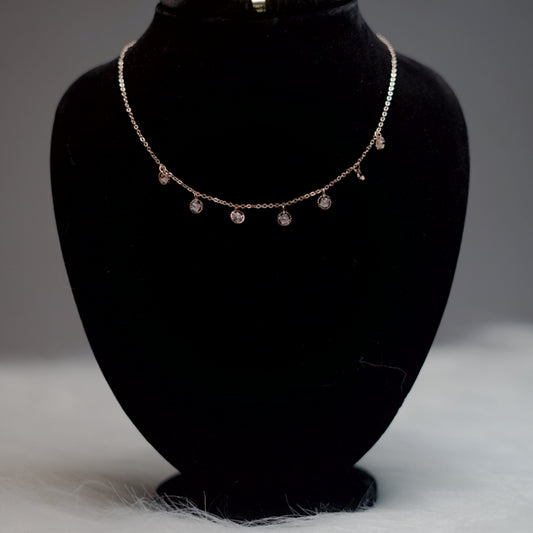Dainty rose gold necklace displayed on a black velvet stand, showing its crystal drop accents and extender chain at the back.