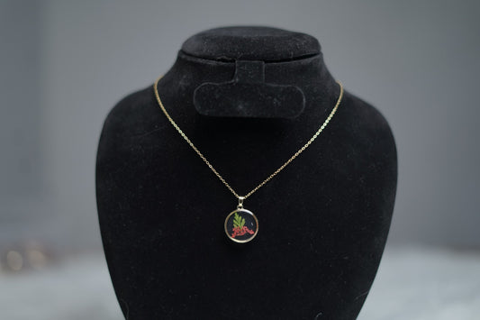 Crimson Leaf Necklace on jewelry stand with botanical print detail.