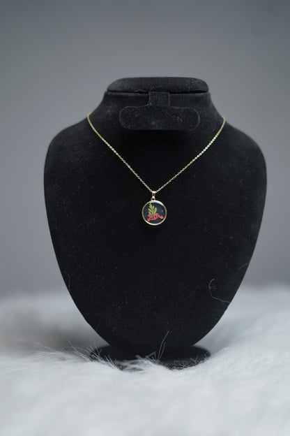 Round resin pendant necklace with red floral design displayed on stand.
