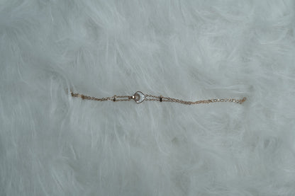 Dual-chain bracelet featuring a center heart-in-ring design, displayed on a furry white surface.