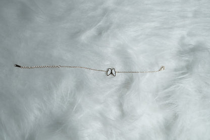 Rose gold bracelet with the white butterfly side featured, resting on fur.