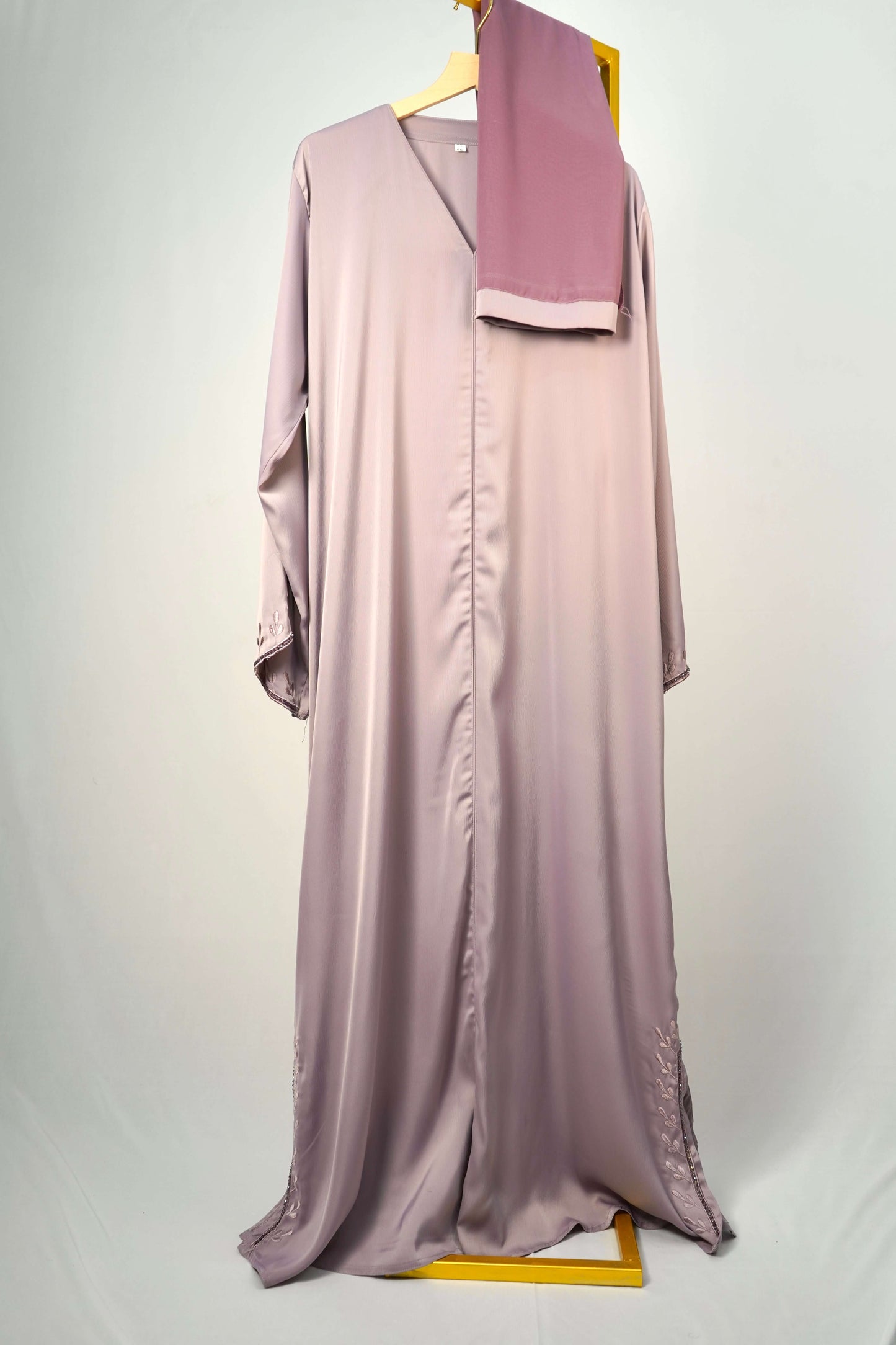 he Tiktok Indonesian Abaya in dusty purple, hanging with its matching scarf to showcase the full design and color.