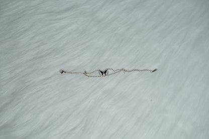 A dainty rose gold bracelet laid flat on soft fur, highlighting the butterfly pendant.