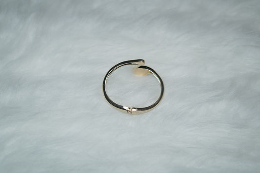 Hand wearing gold sculptural bangle with futuristic open-ended droplet design.