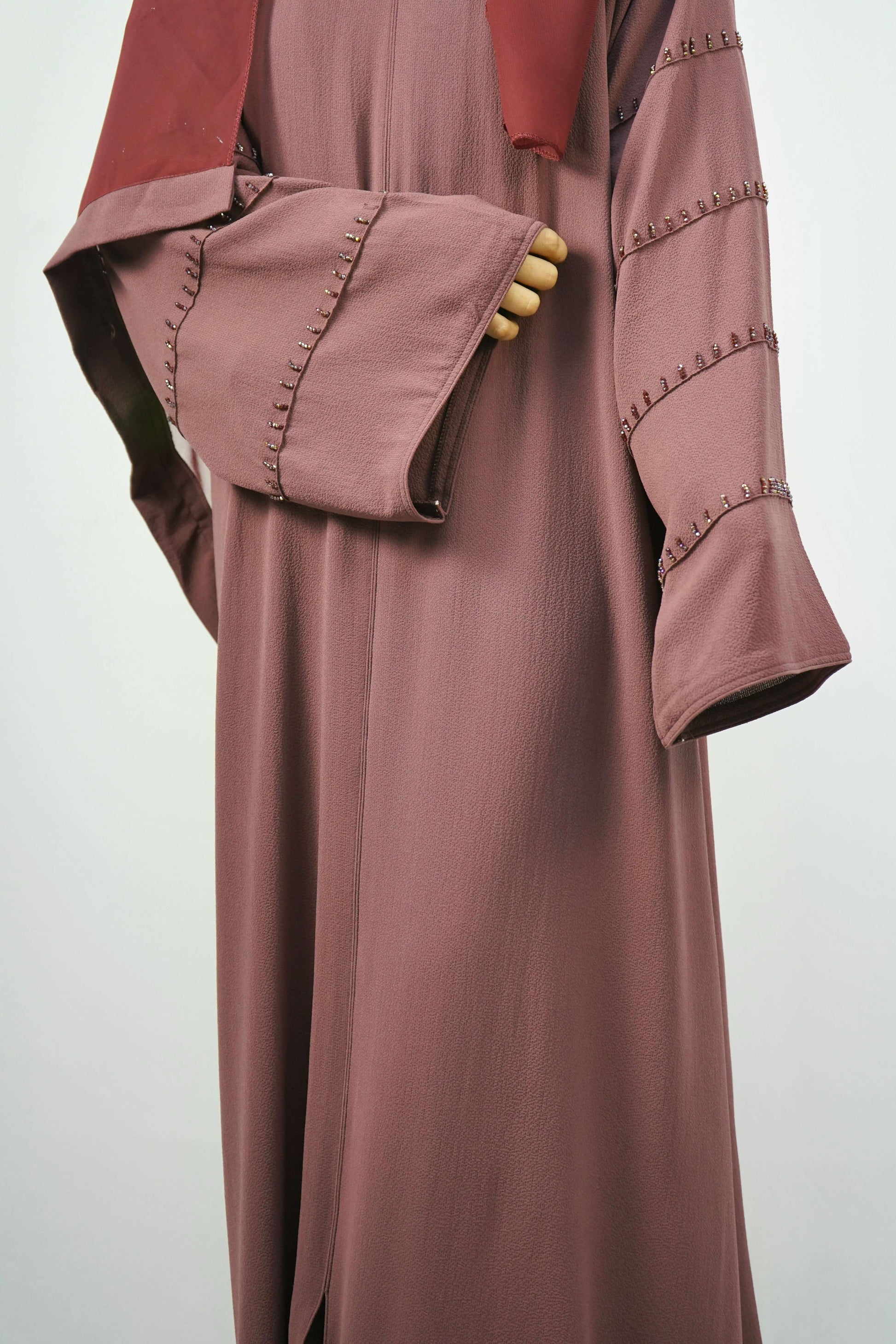 A front view of a woman wearing the Korean Bubble Abaya in Old Mauve, showcasing the elegant drape and the studded sleeves.