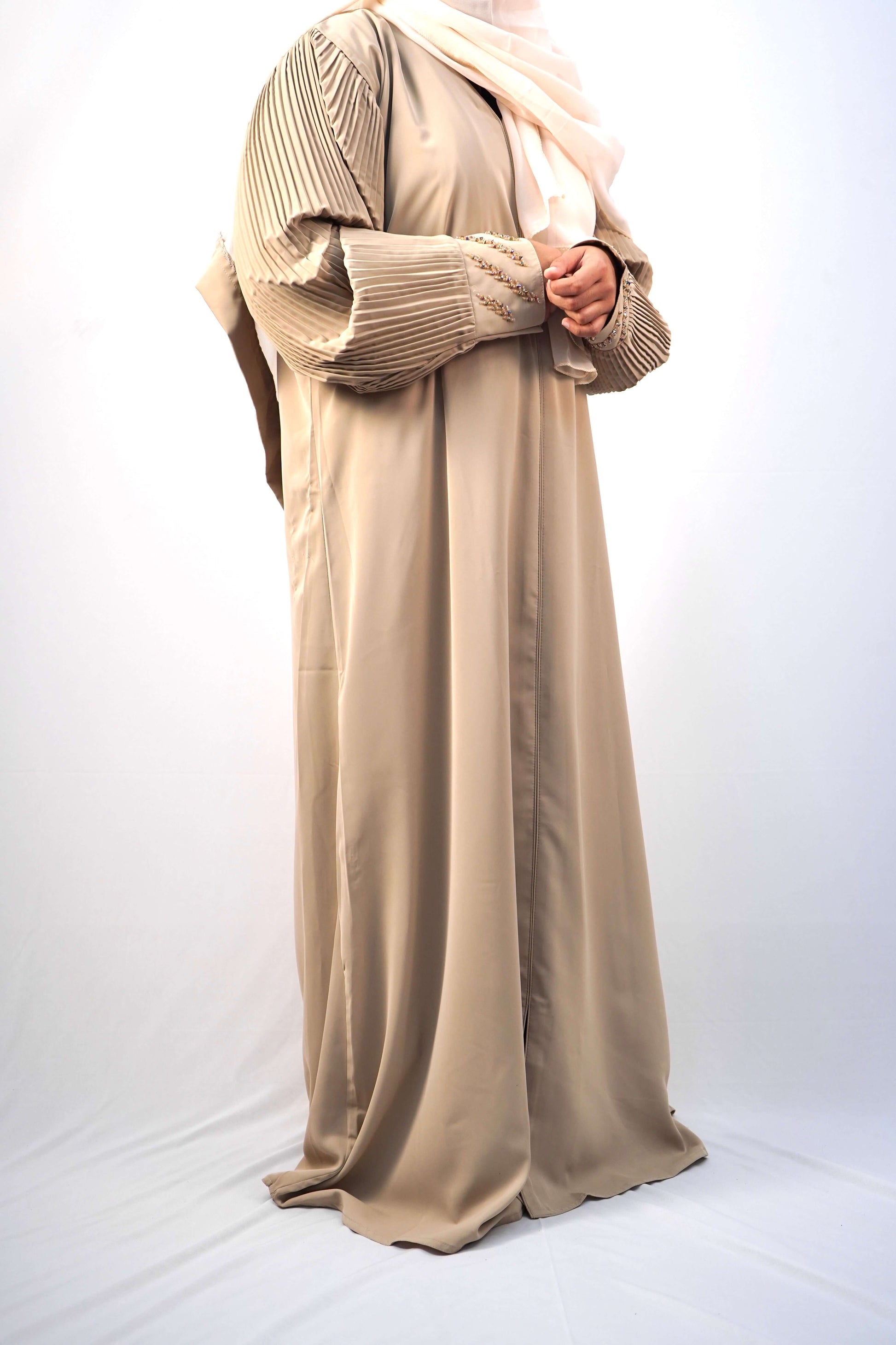 A model wearing the Korean Alqa Nidha Abaya, showcasing the pleated sleeves and matching light beige hijab.